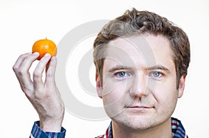 Man holding tangerine in right hand near his head