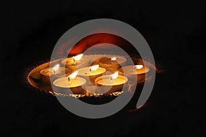 Man holding tealight wax candles or diya lamp in hand in dark night.