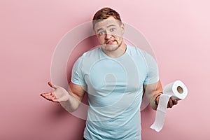 Man holding toliet tissue and looking at the camera with clueless expression