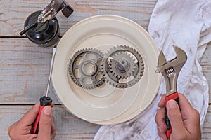 A man holding tools over a gear