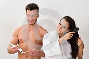 Man holding tooth brush and her wife combing her hair