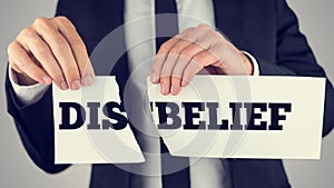 Man holding torn paper with the words Dis-Belief