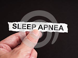 A man holding a torn piece of paper with the words Sleep Apnea on it in his hand