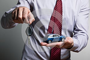 A man holding a toy car and keys in his hands