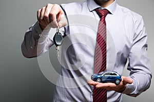 A man holding a toy car and keys in his hands