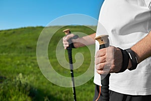 Man holding tracking sticks on green grass background.