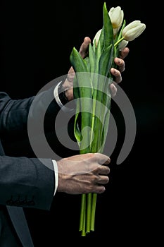 Man holding tulips in hands on black, international women`s day concept