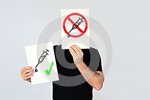 Man holding two cards against and in favor of coronavirus vaccine. Empty copy space