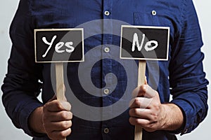 man holding two chalkboards with yes and no answers - YES and NO - Evaluation and decision making concept