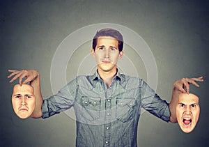 Man holding two different emotion masks