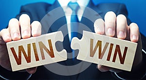 Man holding two puzzles with Win-Win words. A negotiation strategy makes all parties succeed. Mutual benefit and good contract