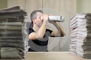 Man holding two twisted roll newspaper. Metaphor or allegory with binoculars. Selective focus on the face