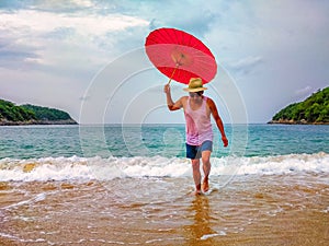 Man holding umbrella on a beach. Tropical vacation and travel