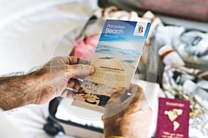 Man holding up beach travels brochure