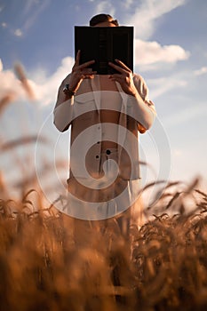 man holding up Bible in a wheat field