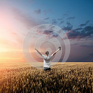 Man holding up Bible in a wheat field