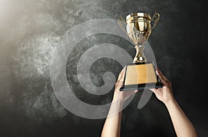 a man holding up a gold trophy cup with grunge wall background c