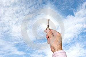 Man holding up key against bright sky