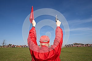 Man holding up a starter gun and flag