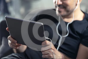 Man holding using digital tablet and headphones sitting on a sofa. Online education, working, video call