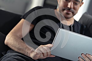 Man holding using digital tablet and headphones sitting on a sofa. Online education, working, video call