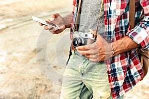 Man holding vintage photo camera and using mobile phone