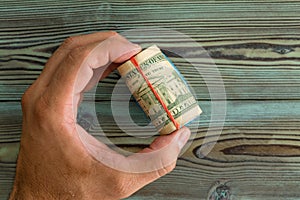 Man holding a wad of rolled USD banknotes