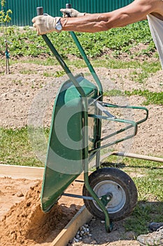 Man holding wheelbarrow for transporting sand