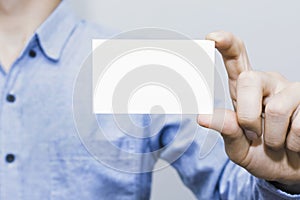 Man holding white business card on concrete wall background