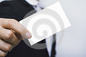 Man holding white business card on concrete wall background