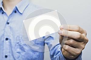 Man holding white business card on concrete wall background,mockup template