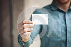 Man holding white business card on concrete wall