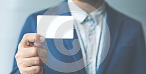 Man holding white business card,Man wearing blue shirt and showing blank white business card. Blurred background. Horizontal mocku