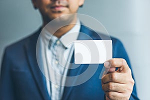 Man holding white business card,Man wearing blue shirt and showing blank white business card. Blurred background. Horizontal mocku