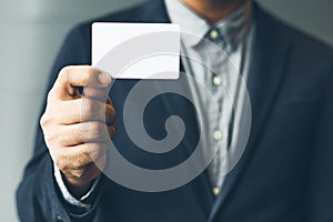 Man holding white business card,Man wearing blue shirt and showing blank white business card. Blurred background. Horizontal mocku