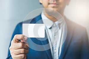 Man holding white business card,Man wearing blue shirt and showing blank white business card. Blurred background. Horizontal mocku