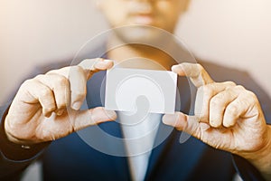 Man holding white business card,Man wearing blue shirt and showing blank white business card. Blurred background. Horizontal mocku