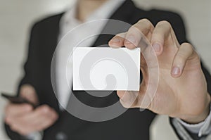 Man holding white business card,Man wearing white shirt and showing blank white business card. Blurred background. Horizontal mock