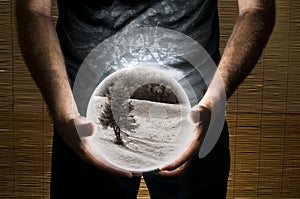 Man Holding White Sphere with Sepia Landscape Picture Inside