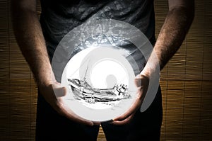 Man Holding White Sphere with a Ship Wreck Inside