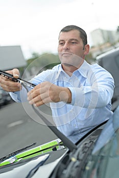 Man holding windscreen wiper on car