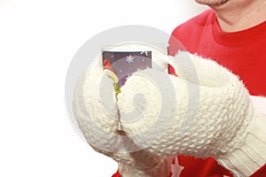 Man holding winter cup close up on dark background. Male hands in gloves holding cozy mug tea or coffee. Winter and Christmas time