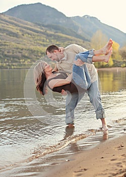 Man holding woman playfully on lake beach