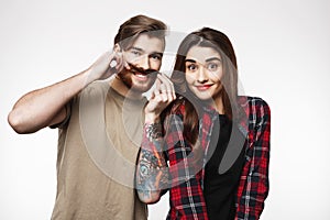 Man holding woman`s hair as it is moustache, smiling happily.