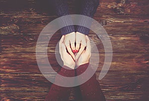 Man holding woman`s hands top view image on dark wooden backdrop. Couple in love consept.