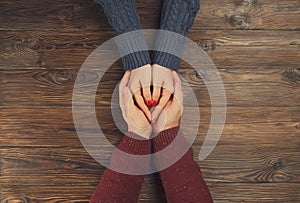 Man holding woman`s hands top view image on dark wooden backdrop. Couple in love consept.