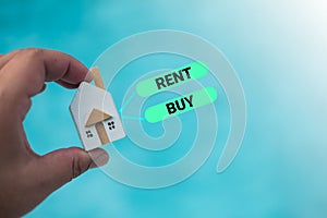 Man holding wood home with deciding whether to buy or rent for the home