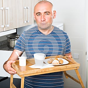 Man holding wood salver of breakfast in kitchen photo