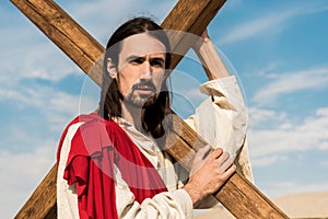 Man holding wooden cross against blue sky