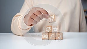 Man holding a wooden cube with printed educational symbols, E-learning education, internet lessons and online webinar. Education